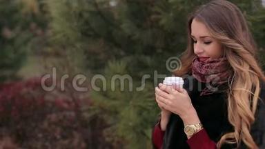 带着一杯咖啡在公园户外散步的<strong>年轻笑</strong>女。