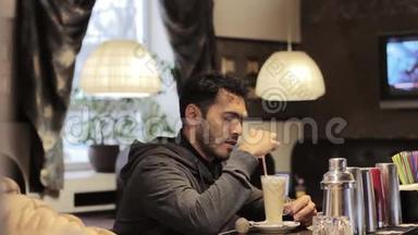 一个迪拜年轻人在咖啡馆里搅拌糖和喝咖啡