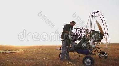 汽车滑翔伞在日落时分用木制螺旋桨站在田野里，飞行员伸出降落伞，