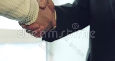 与一个年轻的商人握手时，一个老人用粗糙的、划伤的手握手。