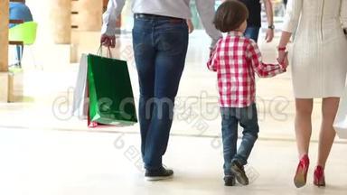 快乐家庭圣诞购物中心。 带着母亲和父亲的男孩。 带包的家长和孩子