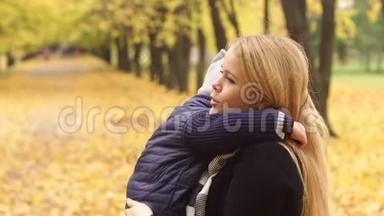 妈妈在秋天公园里<strong>轻轻地</strong>拥抱她的儿子。