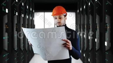 一个戴着安全头盔的英俊男子在后台阅读带有大型系统服务器的蓝图