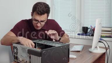 年轻的专业工人试图用螺丝刀修理办公室里的电脑，并升级电脑硬件