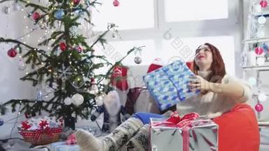 美丽的年轻快乐的女人把一个礼物盒扔到圣诞树附近的空中。 慢动作。 3840x2160