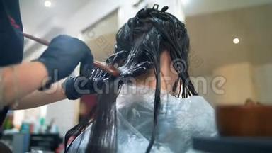 在沙龙里的白种人女人用专业的化妆师做头发处理。 专业洗头，按摩面膜