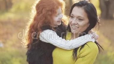 一位美丽的<strong>妈妈</strong>和她可爱的女儿正在秋天的公园里散步。 <strong>妈妈</strong>把女儿抱在<strong>怀里</strong>。 他们