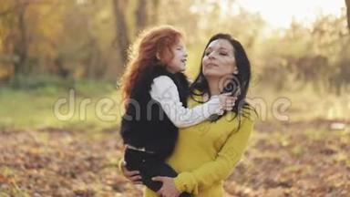 一位美丽的<strong>妈妈</strong>和她可爱的女儿正在秋天的公园里散步。 <strong>妈妈</strong>把女儿<strong>抱</strong>在怀里。 他们