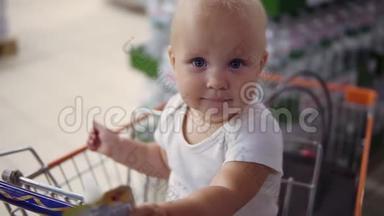 小婴儿坐在超市的<strong>购物</strong>车里，等着她的父母去<strong>购物</strong>。 带着家庭<strong>购物</strong>