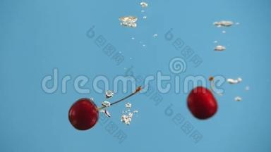 两颗樱桃在蓝色背景下缓慢地<strong>落入</strong>水中