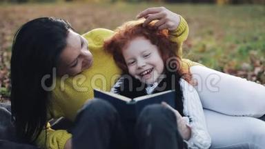 妈妈和她的小女儿坐在秋天的部分，读了一<strong>本书</strong>。 他们说得很好。 秋天森林里的幸福家庭