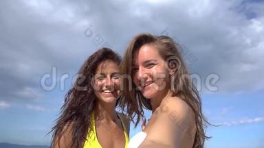 两个女人在海滩上用<strong>手机</strong>自拍，微笑着<strong>旋转</strong>着享受大自然的假期