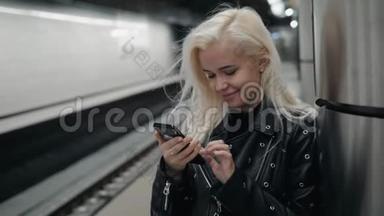 年轻的金发旅行女人手里拿着手机在火车站台上等着。 <strong>公共交通</strong>。