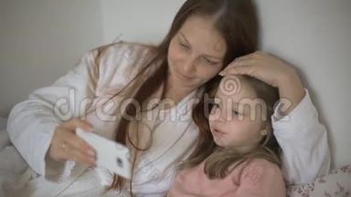 一个小女孩和妈妈躺在床上，看着智能手机屏幕上的卡通片、儿童和数字
