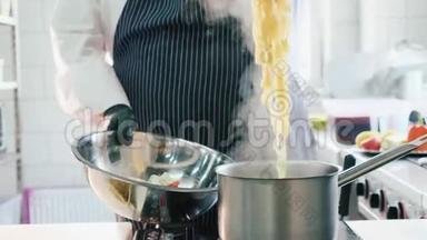 厨师在商业厨房用火钳取出一个沸腾的意大利面食。