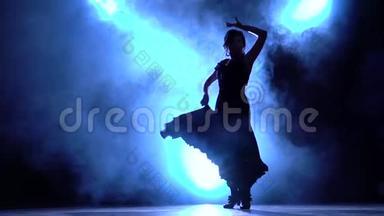 <strong>舞蹈</strong>演员穿着别致的裙子，跳着弗拉门戈的燃烧舞。 从后面发光。 <strong>烟</strong>雾背景。 剪影。 慢慢