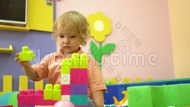 金发学龄前幼儿在幼儿园玩多种颜色的积木。 儿童发展