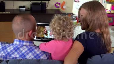 幼儿女孩和<strong>爸爸妈妈</strong>在平板电脑上看家庭电影。
