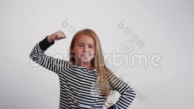一个有趣的女孩握紧拳头，显示出力量。 女孩模仿强壮的男人。
