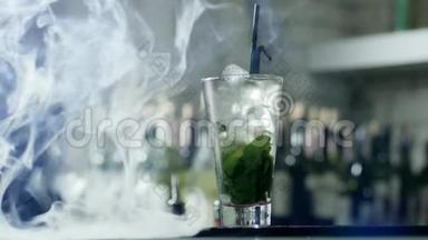 酒精鸡尾酒，冰块和绿色叶子，大玻璃，黑色塑料吸管，站在酒吧的桌子上，薄雾