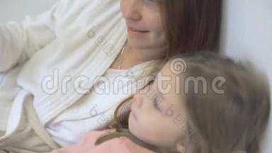 一个小女孩和妈妈躺在床上，看着智能手机<strong>屏幕</strong>上的<strong>卡通</strong>片、儿童和数字