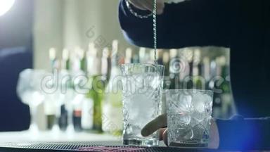 酒吧勺子在酒吧老板手中搅拌杯中的冰块在酒吧柜台的背景上