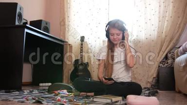 十几岁的女孩在家里坐在地板上用智能手机听耳机里的音乐
