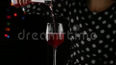红酒灌杯.. 女人在黑暗中喝一杯红酒。 节日气氛。 慢动作