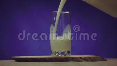 蓝色背景上有牛奶的杯子.. 透明库什文的牛奶倒入玻璃杯中。