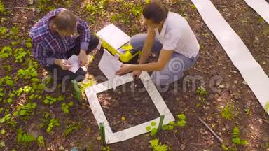 两位生态学家在森林中采集土壤样本