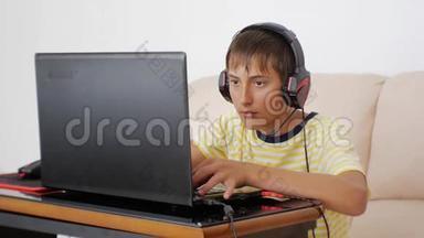 使用笔记本电脑的青少年。 电子游戏上瘾的青少年耳机粘在笔记本屏幕上按下键盘。