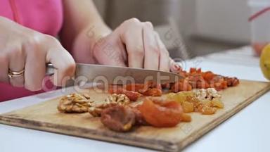 一位年轻的<strong>家庭</strong>主妇用一把刀在砧板上切果干杏子. 健康<strong>饮食</strong>观念