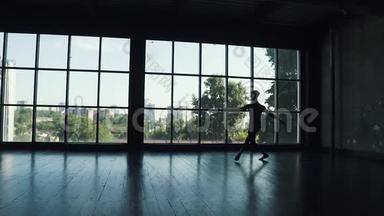一位<strong>芭蕾</strong>舞演员的<strong>剪影</strong>，以一扇大窗户为背景。 <strong>舞蹈</strong>演员跳得很高。 慢动作