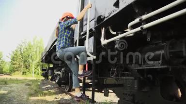 一个年轻的女火车司机走下楼梯，走到火车旁边。