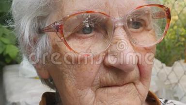 <strong>戴眼镜</strong>的老妇人向前看，微笑着。 <strong>戴眼镜</strong>的快乐奶奶花时间在户外的肖像。 情绪