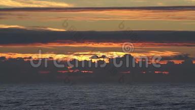 海面上夕阳西下，有着小波浪，云朵和美丽的红色阳光，水面上有倒影