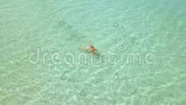 美丽的女人游泳在晶莹剔透的海水无人机从上面看。 女人沐浴在绿松石的海水中