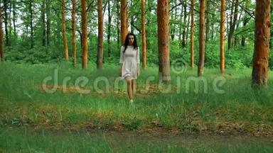 年轻可爱的黑发女孩穿着白色连衣裙在树林里散步