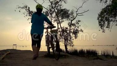 骑自行车的女人在海边骑自行车走路的剪影，伸展运动。