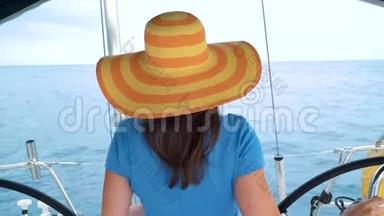 穿着黄色帽子和蓝色裙子的女人站在游艇上，在海洋的夏季微笑