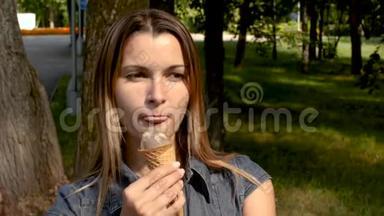 年轻迷人的女人在公园里吃<strong>冰</strong>淇淋。 那个女孩在绿树丛中吃<strong>冰</strong>淇淋. 炎炎<strong>夏日</strong>清凉