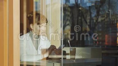 年轻女子在咖啡馆里打字。 白种人妇女戴着花边羊毛围巾的肖像，在她的手机上输入一条信息