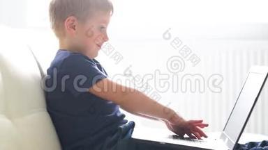 快乐男孩玩电脑的肖像。 有魅力的孩子家里有笔记本电脑。 娱乐技术，未来主义