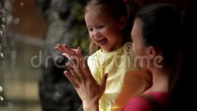 妈妈和可爱的女儿玩小瀑布。 他们在母亲节一起玩得很开心。 瀑布