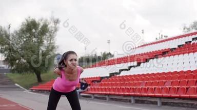 运动员在比赛前在运动场热身. 那个黑发女孩正在向前倾斜。 穿粉色衣服的女孩