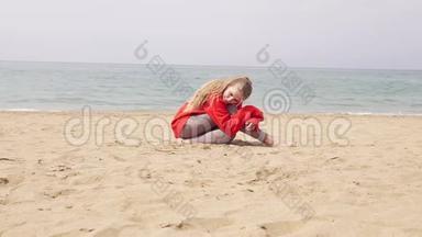 金发女孩坐在海边的沙滩上，摆姿势拍照