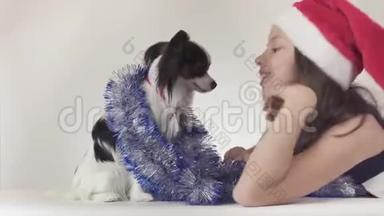 圣诞老人戴着圣诞老人的帽子、戴着狗的美丽的少女在新年里`他的小罐子快乐地玩耍