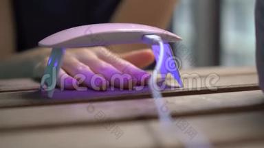一位女士用在紫外线下变硬的凝胶抛光来修指甲