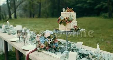 在雾蒙蒙的森林里为浪漫的约会服务的桌子。桌上装饰着美味的双层蛋糕和花束