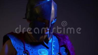 穿着沉重头盔、皮甲和红色雨衣的罗马角斗士注视着站在紫外线下的摄像机
